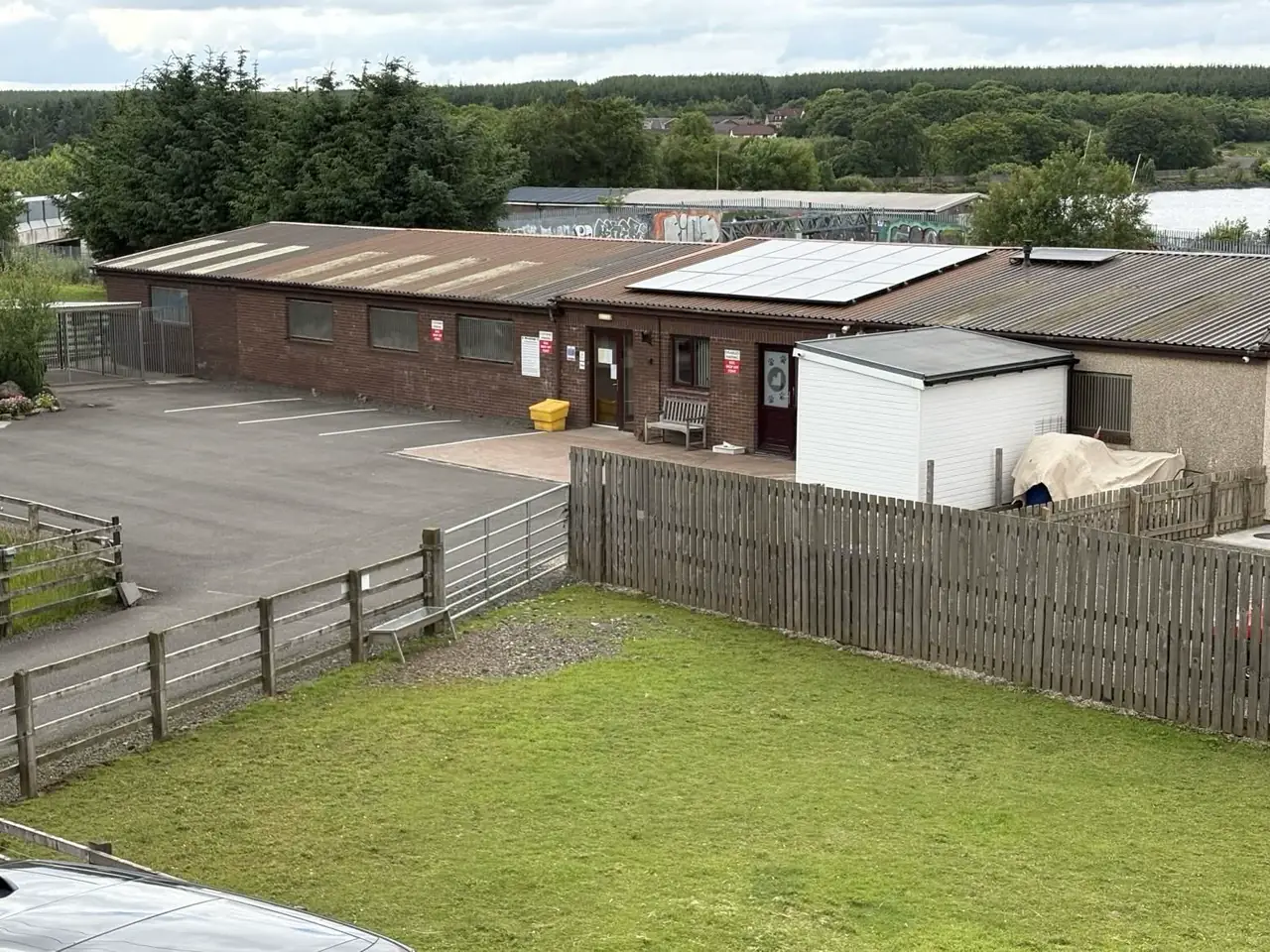 The LochView kennels building beside the loch, with a fenced grass exercise paddock